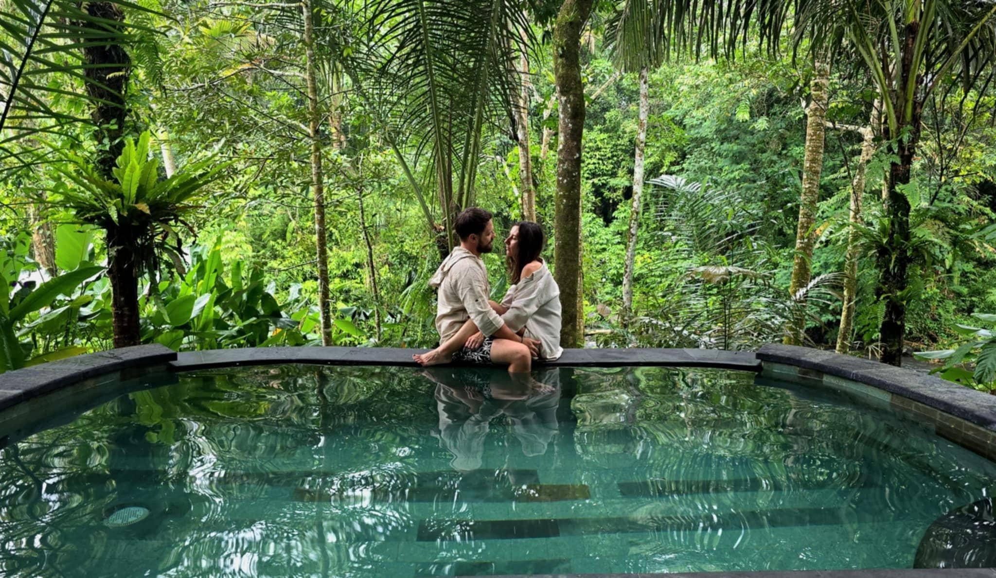 Couple by an infinity pool surrounded by tropical jungle, East Bali