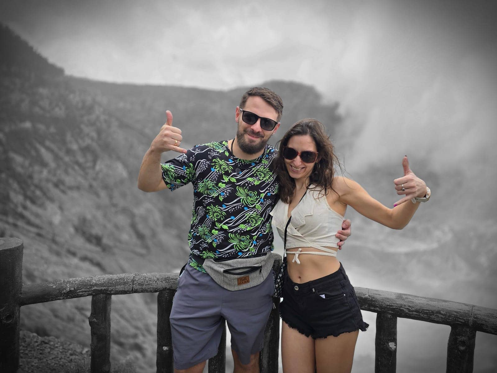 A couple giving thumbs up at the viewpoint over the misty Tangkuban Perahu volcano crater in West Java