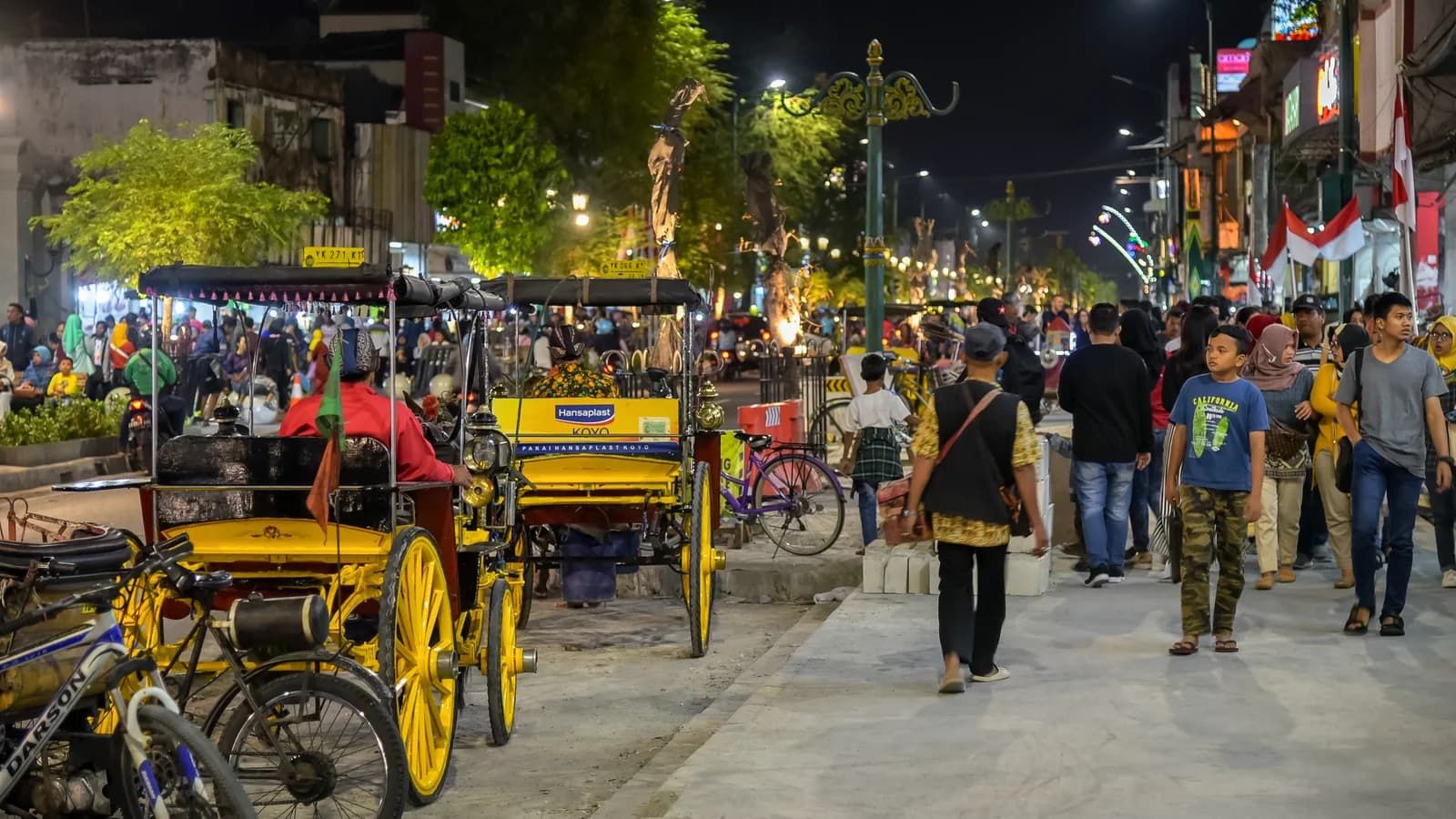 Horse-drawn carriages and pedestrians on Malioboro street at night in Yogyakarta