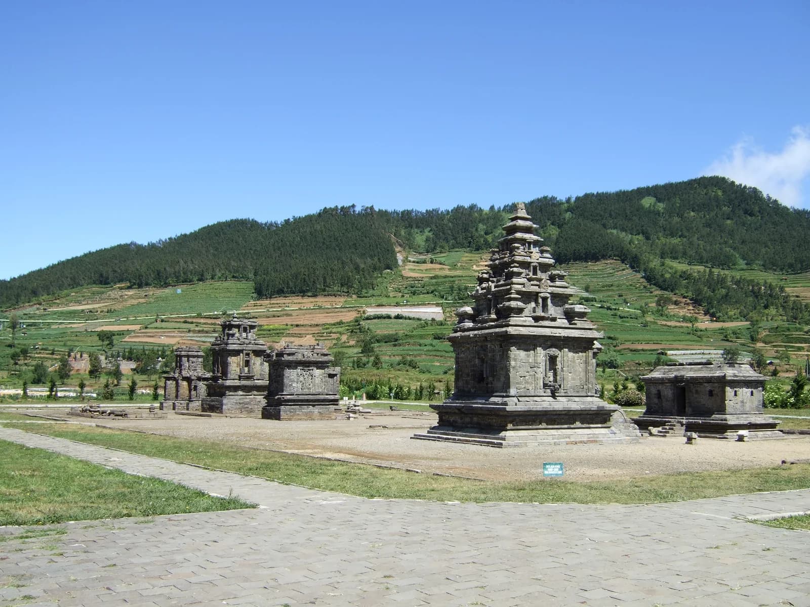 Stone temples of the Arjuna group on the Dieng Plateau with green hills behind