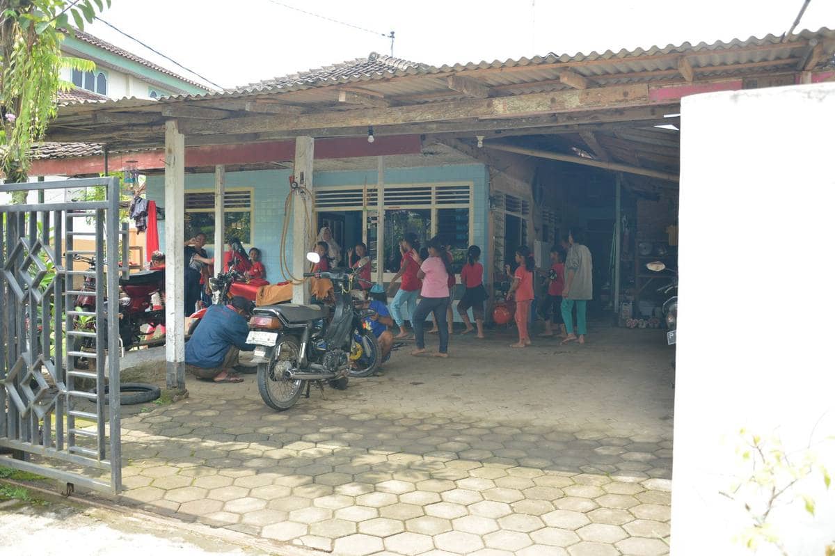 A courtyard in Yogyakarta with people and parked motorcycles