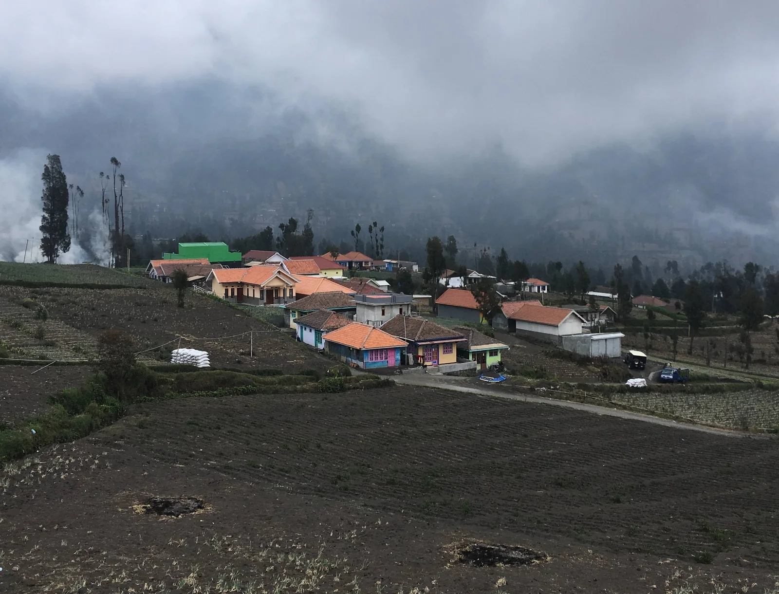 Red-roofed houses and fields in Cemoro Lawang beneath low cloud