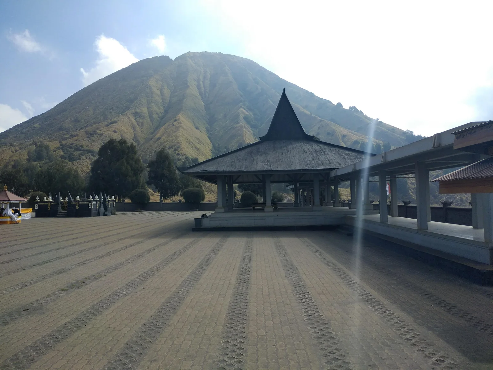 The courtyard and pavilion of Pura Luhur Poten temple below a steep mountain slope