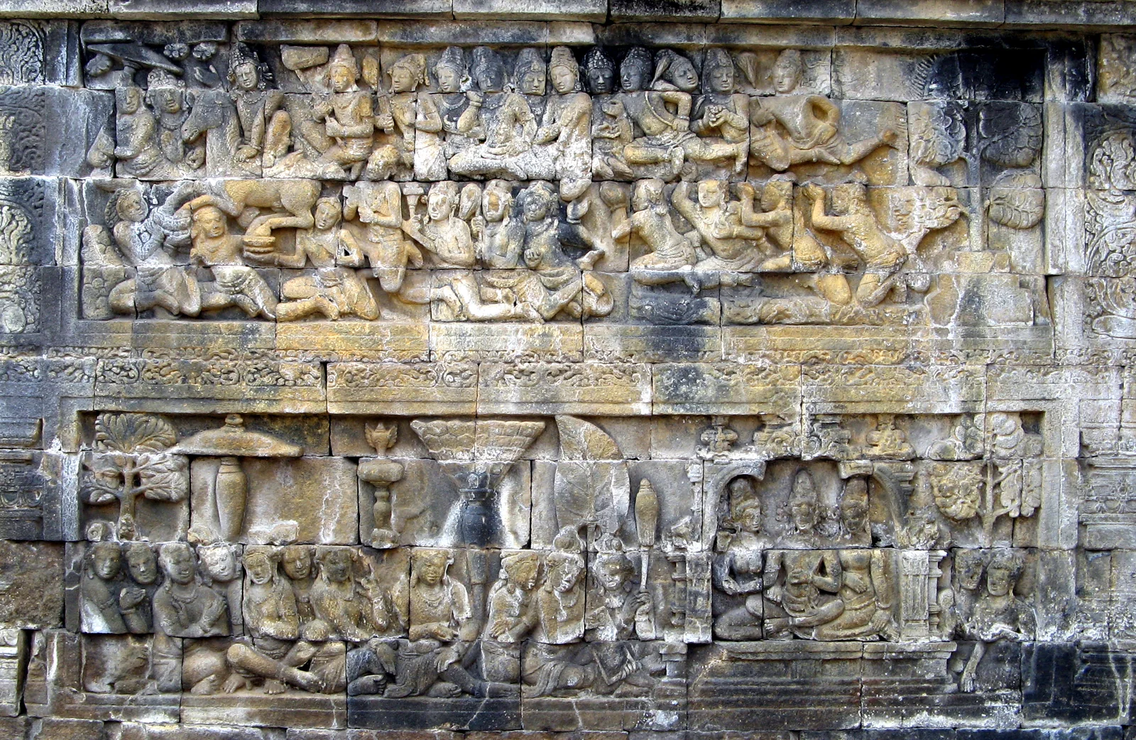 A Borobudur stone relief showing figures and a horse in two horizontal bands
