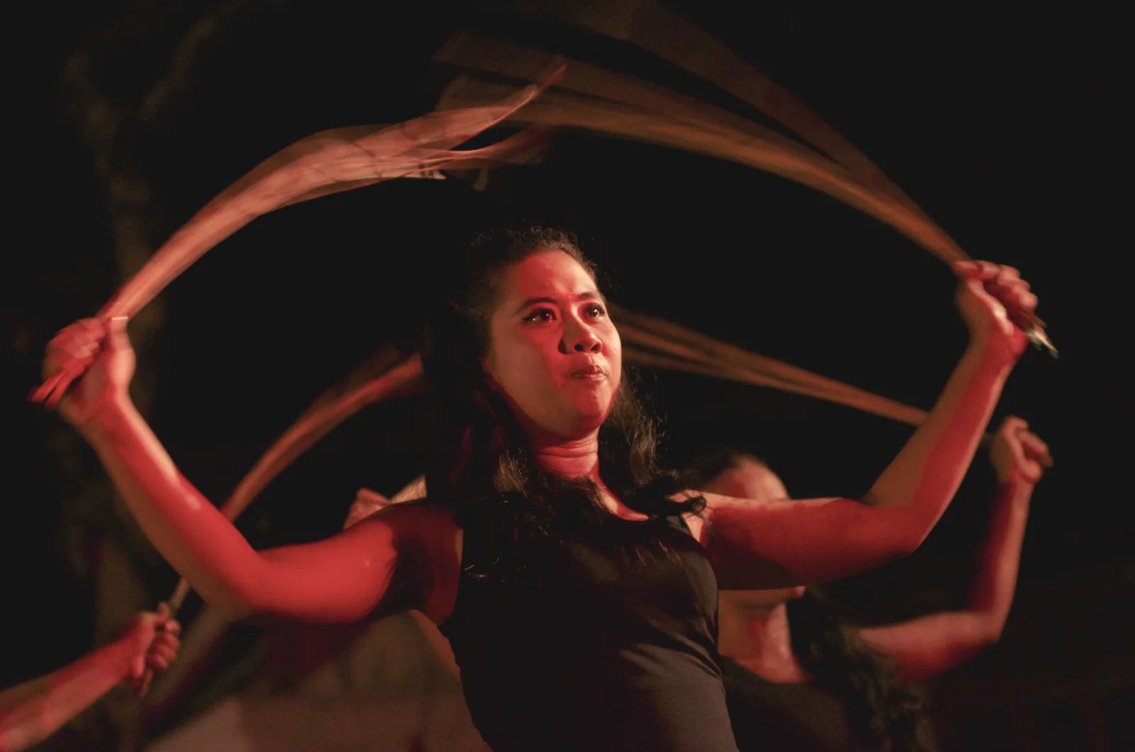 A Teater Satu Lampung actor with raised arms on a dark stage at UWRF 2012