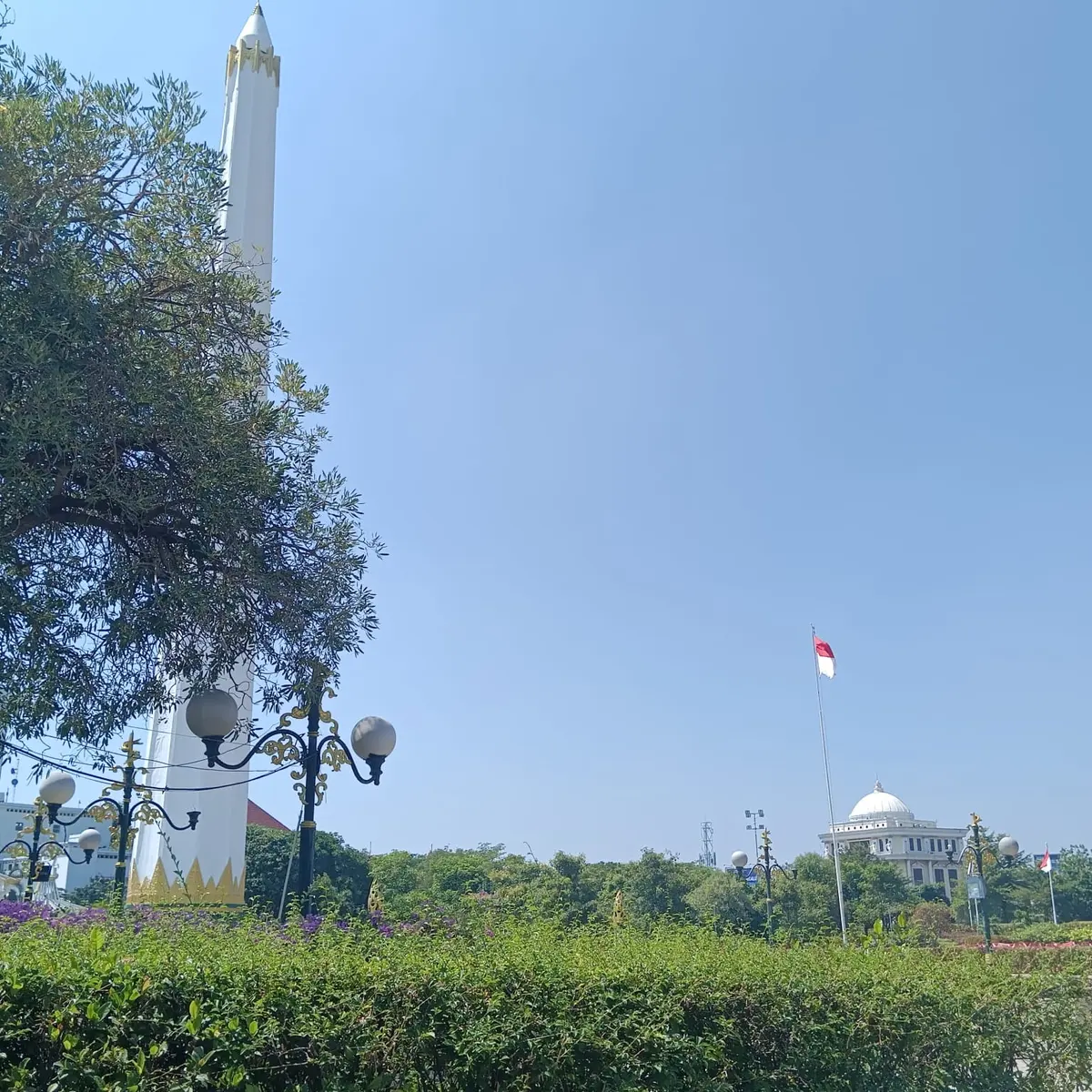 Biały pomnik Tugu Pahlawan i indonezyjska flaga na tle nieba