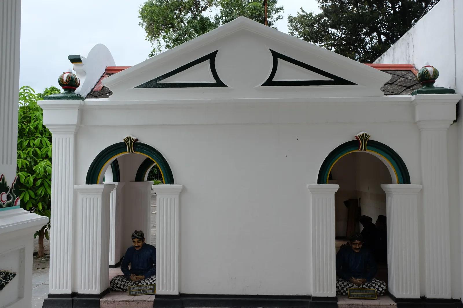 A white wall with two decorated niches and figures inside the Kraton Yogyakarta complex